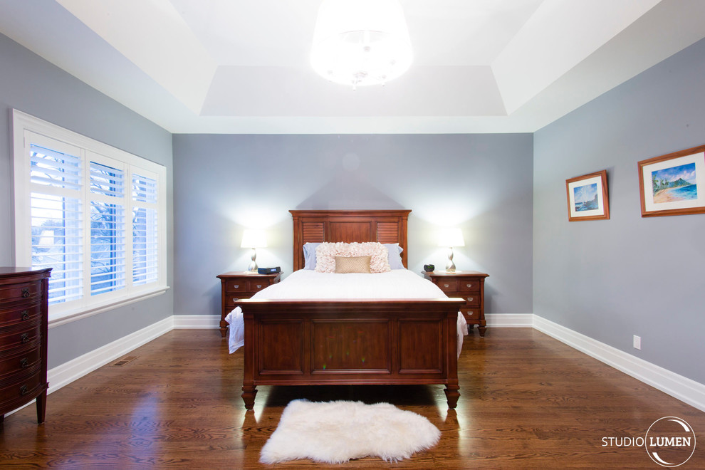 Contemporary master bedroom in Toronto with blue walls and dark hardwood flooring.