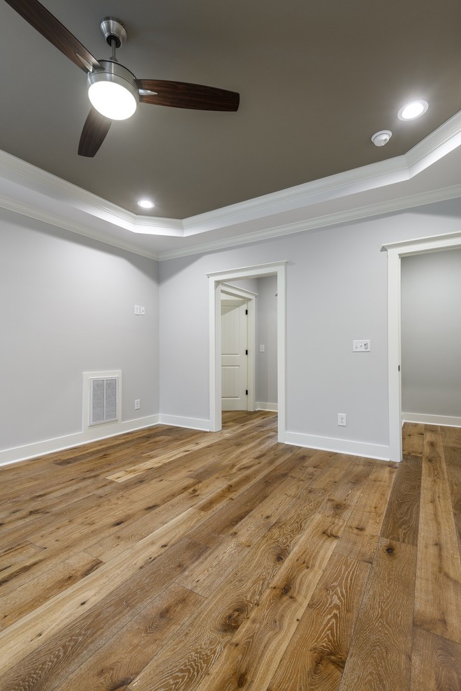 Cette image montre une chambre parentale rustique de taille moyenne avec un mur gris, un sol en bois brun, aucune cheminée et un sol marron.