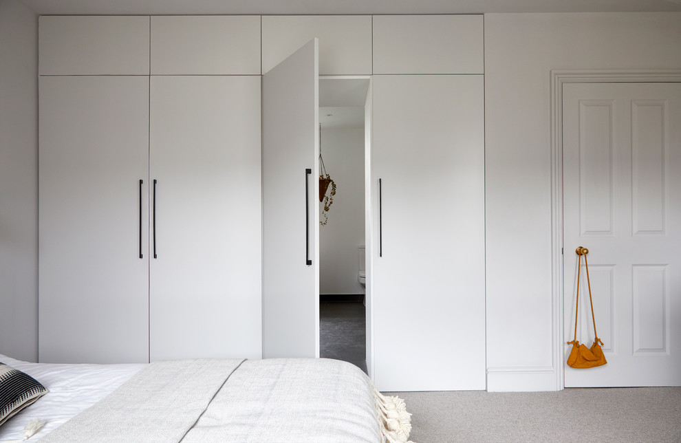 Photo of a large scandi master bedroom in London with white walls, carpet and beige floors.