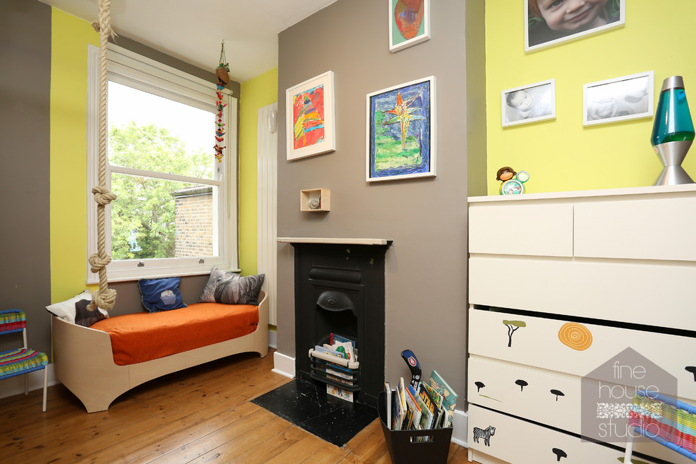 Cette photo montre une chambre d'amis éclectique de taille moyenne avec un mur jaune, un sol en bois brun, une cheminée standard et un manteau de cheminée en métal.
