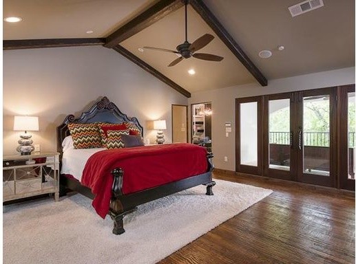 Bedroom - large mediterranean master dark wood floor bedroom idea in Dallas with beige walls, a standard fireplace and a stone fireplace