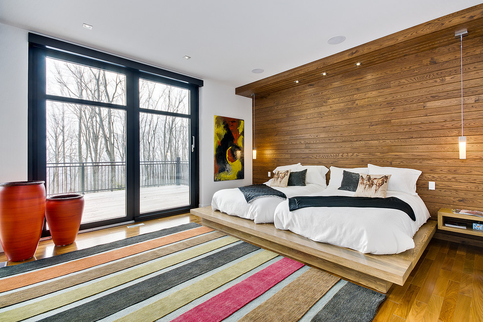 Esempio di una camera degli ospiti contemporanea con pareti bianche, pavimento in legno massello medio e nessun camino