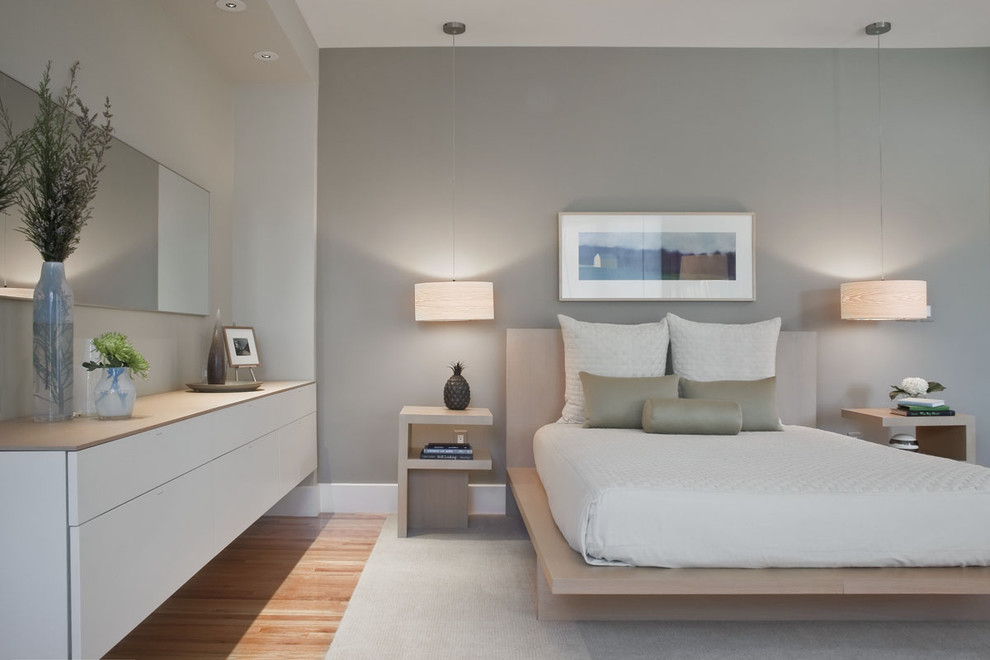Пример оригинального дизайна: спальня в современном стиле с серыми стенами, светлым паркетным полом и акцентной стеной без камина