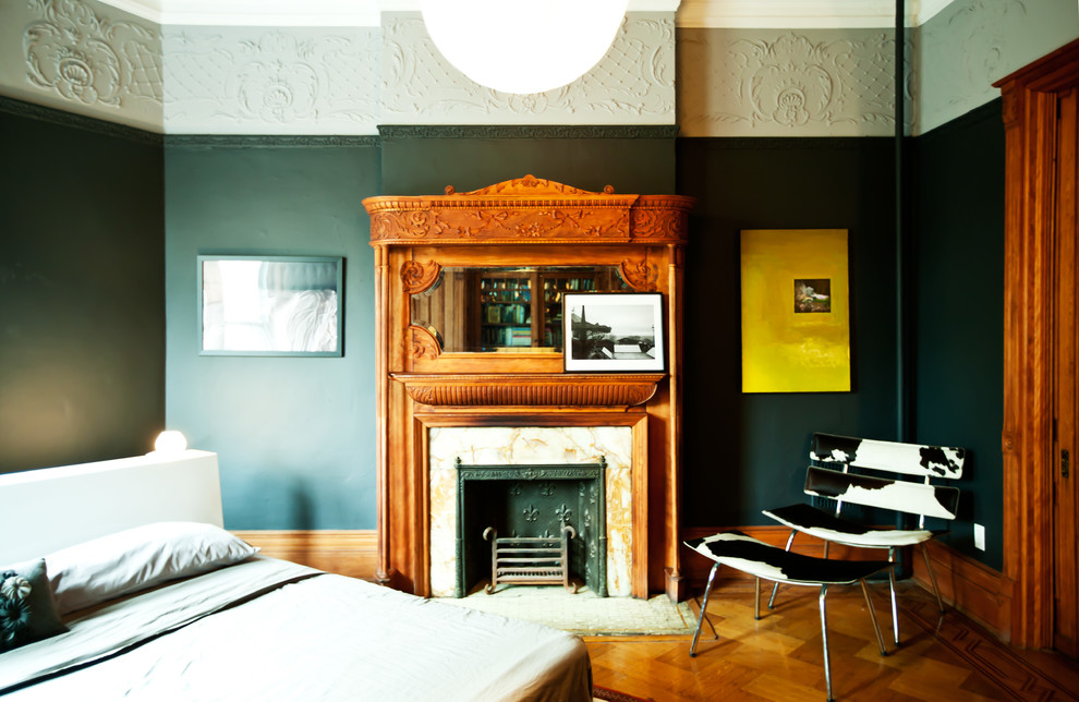 Aménagement d'une chambre contemporaine avec un mur noir, un sol en bois brun et une cheminée standard.