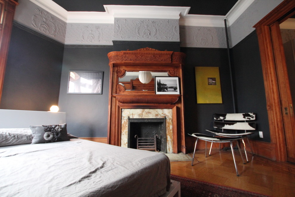 Ejemplo de dormitorio contemporáneo con paredes grises y marco de chimenea de piedra