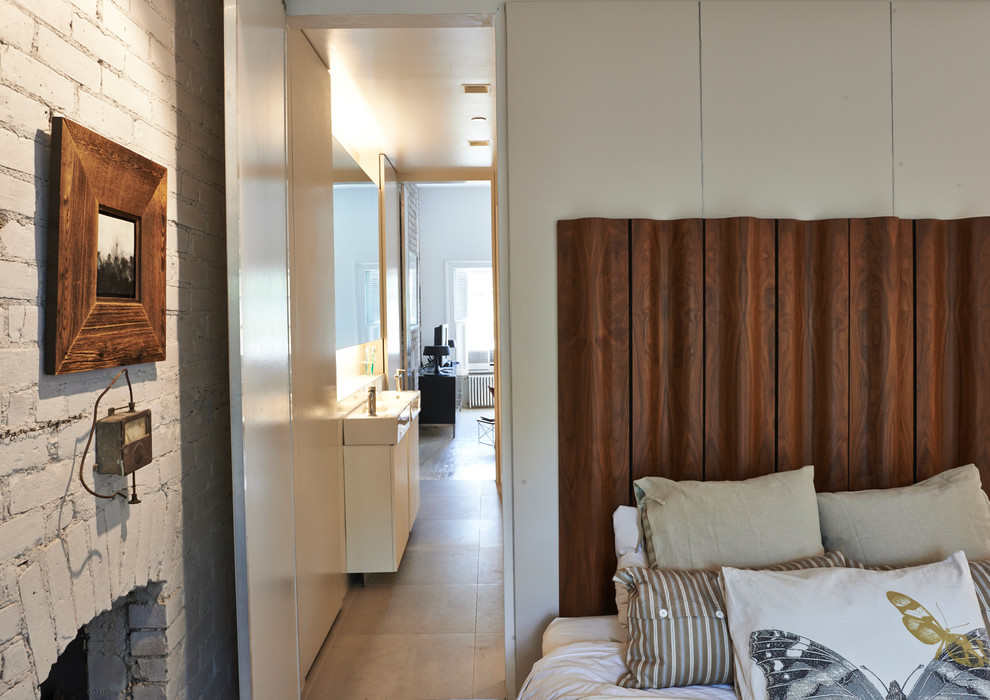 Foto di una piccola camera matrimoniale contemporanea con pavimento in legno verniciato, camino classico, cornice del camino in mattoni, pareti beige e pavimento beige