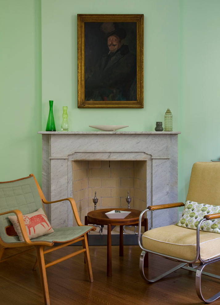 Immagine di una camera degli ospiti chic di medie dimensioni con pareti verdi, pavimento in legno massello medio, camino classico e cornice del camino in pietra