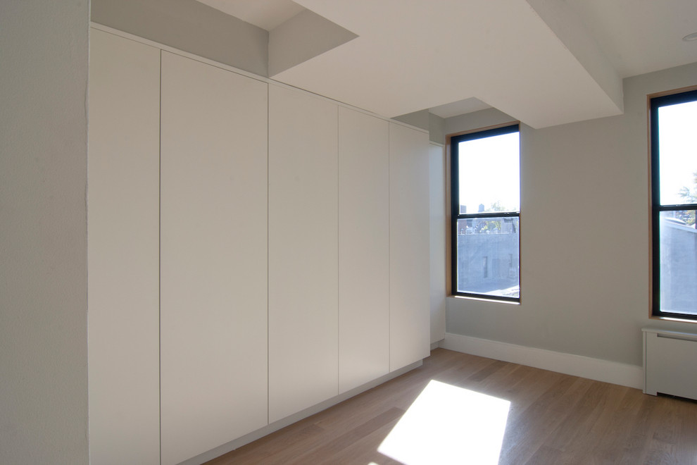 ニューヨークにある中くらいなコンテンポラリースタイルのおしゃれな主寝室 (グレーの壁、淡色無垢フローリング、茶色い床) のインテリア