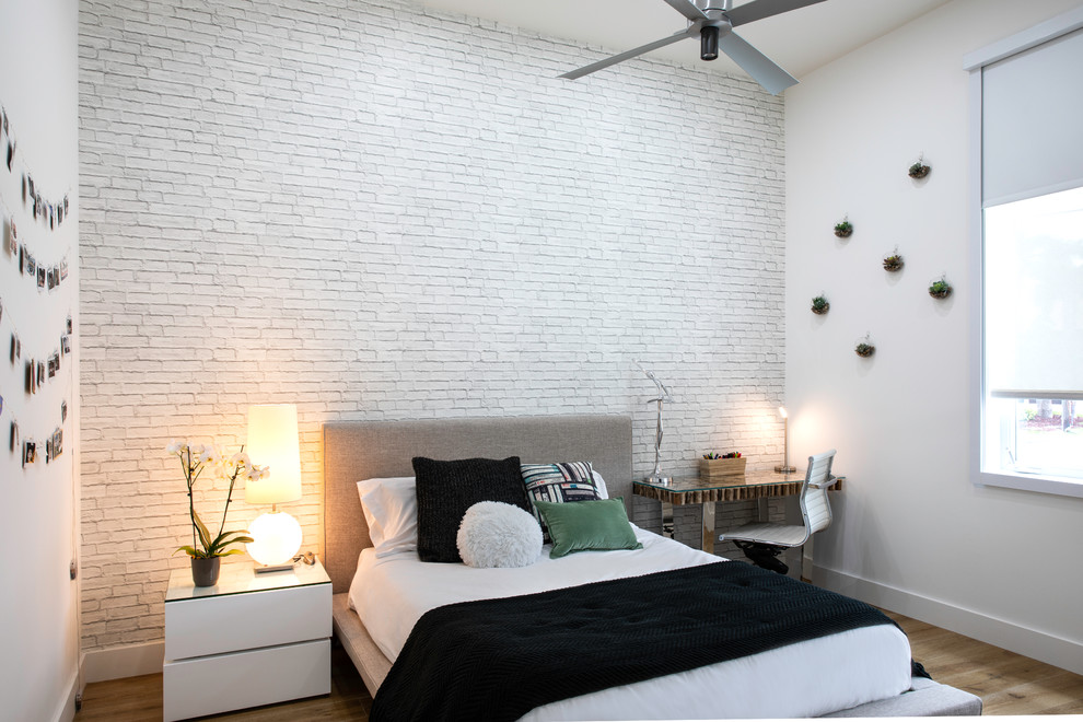Cette image montre une chambre d'amis design avec un mur blanc, un sol en bois brun et un sol beige.