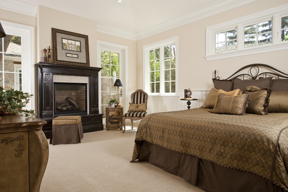 Пример оригинального дизайна: спальня в классическом стиле с бежевыми стенами, ковровым покрытием и стандартным камином