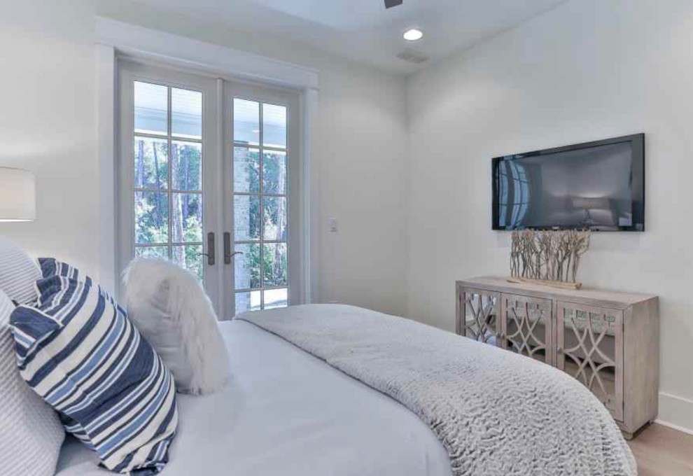 Foto de habitación de invitados costera de tamaño medio sin chimenea con paredes blancas, suelo de madera clara y suelo beige