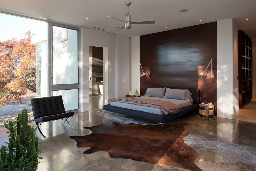 Großes Modernes Hauptschlafzimmer ohne Kamin mit weißer Wandfarbe und Betonboden in Austin