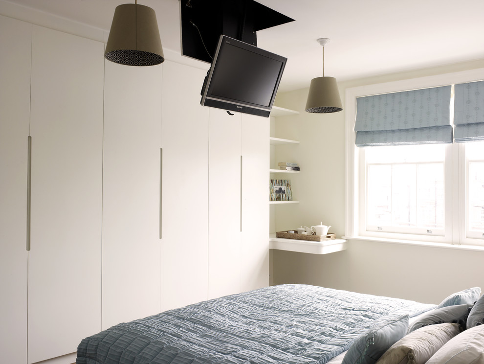 Modernes Hauptschlafzimmer ohne Kamin mit weißer Wandfarbe und braunem Holzboden in London