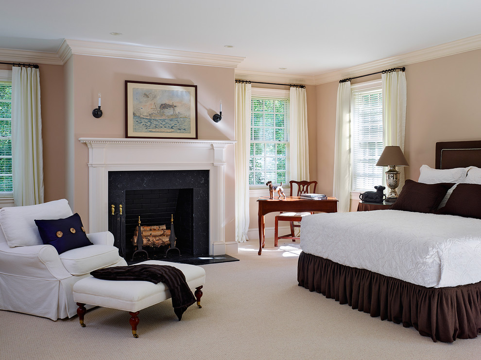 Imagen de dormitorio principal clásico con paredes beige, moqueta, todas las chimeneas y marco de chimenea de piedra