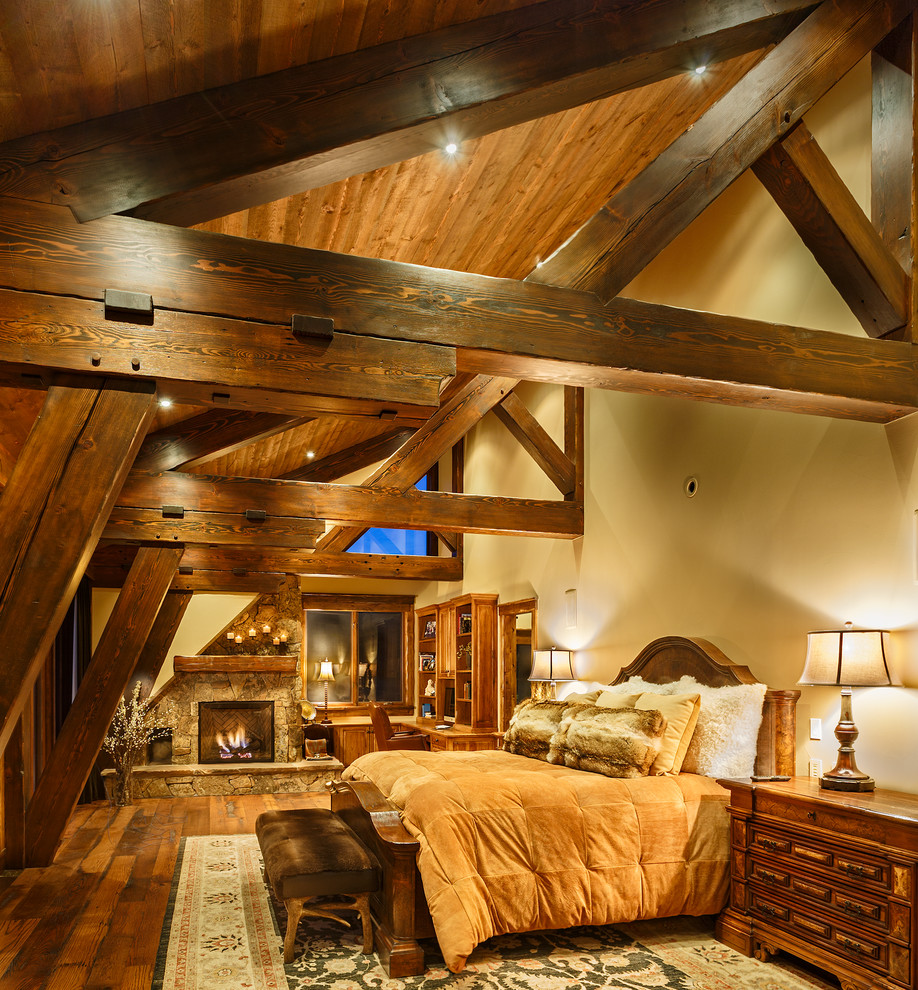 Mittelgroßes Rustikales Hauptschlafzimmer mit dunklem Holzboden, Kamin und Kaminumrandung aus Stein in Denver