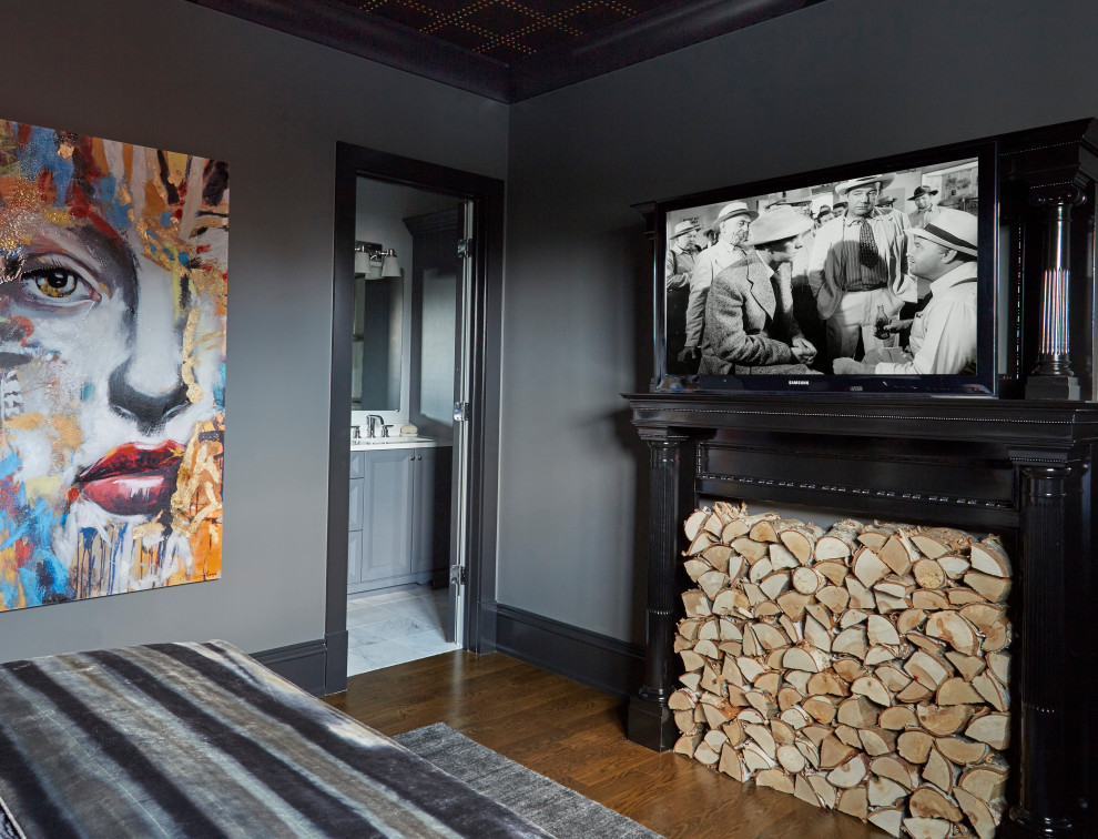Imagen de dormitorio principal actual con paredes grises, suelo de madera en tonos medios, todas las chimeneas, marco de chimenea de madera y suelo marrón