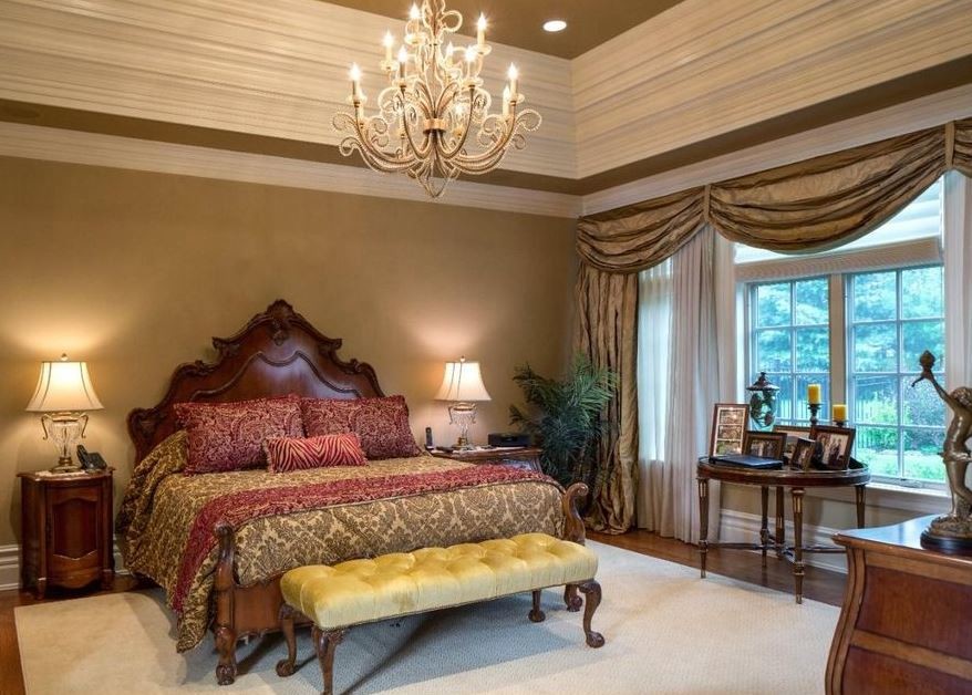 Modelo de dormitorio principal clásico grande con paredes beige, suelo de madera oscura y suelo marrón