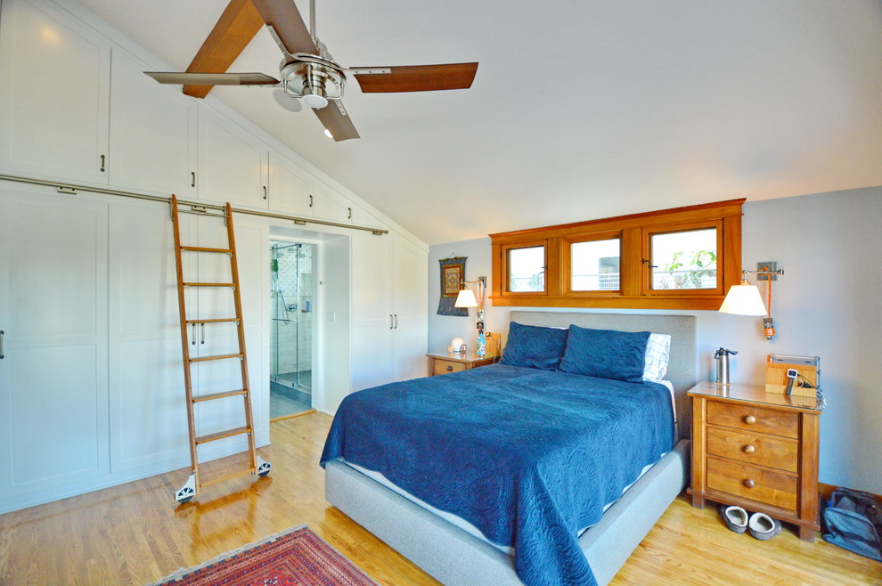 Ejemplo de dormitorio de estilo americano con paredes grises, suelo de madera en tonos medios y suelo marrón