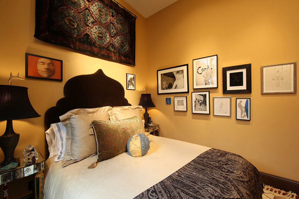 Cette photo montre une petite chambre parentale éclectique avec un mur jaune et un sol en bois brun.