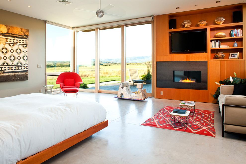 Mittelgroßes Modernes Hauptschlafzimmer mit Betonboden, Kaminumrandung aus Metall, grauer Wandfarbe und Kamin in Denver
