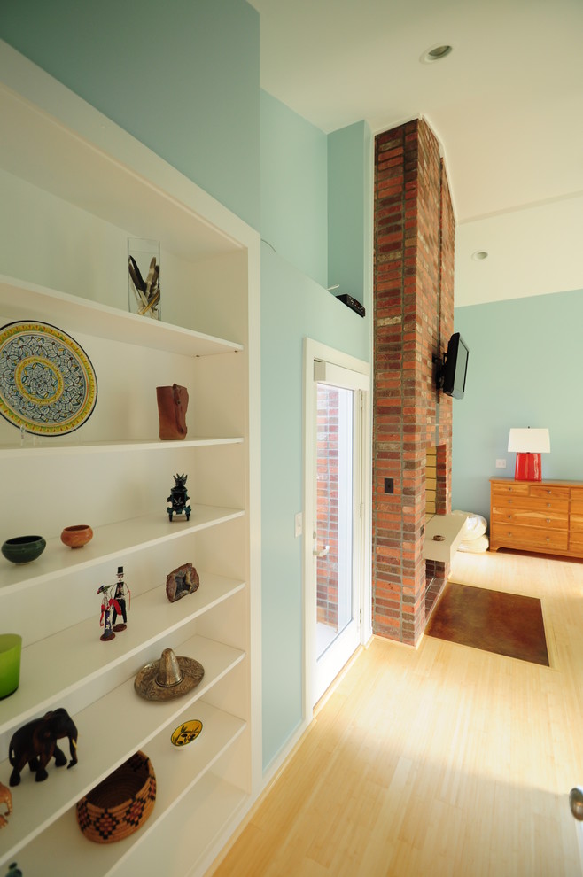Idéer för mellanstora funkis huvudsovrum, med blå väggar, en spiselkrans i tegelsten, ljust trägolv, en standard öppen spis och beiget golv