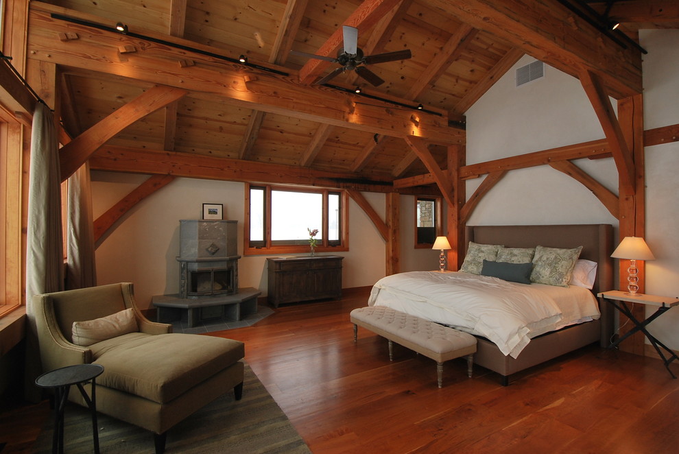 Großes Rustikales Schlafzimmer mit weißer Wandfarbe, braunem Holzboden, Kamin, Kaminumrandung aus Metall und braunem Boden in Sonstige