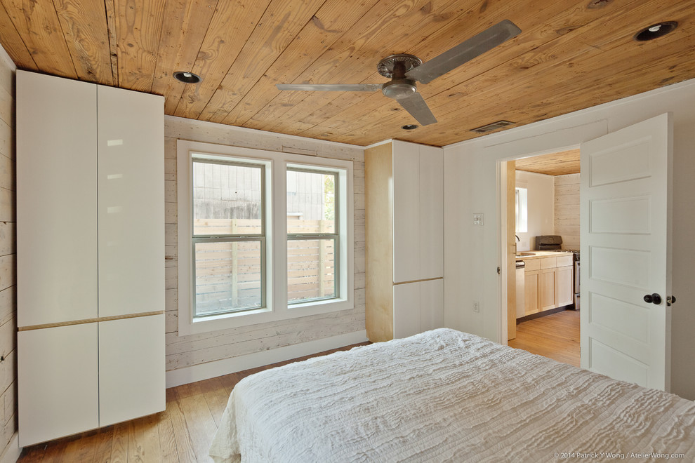 Immagine di una piccola camera matrimoniale design con pareti bianche e pavimento in legno massello medio