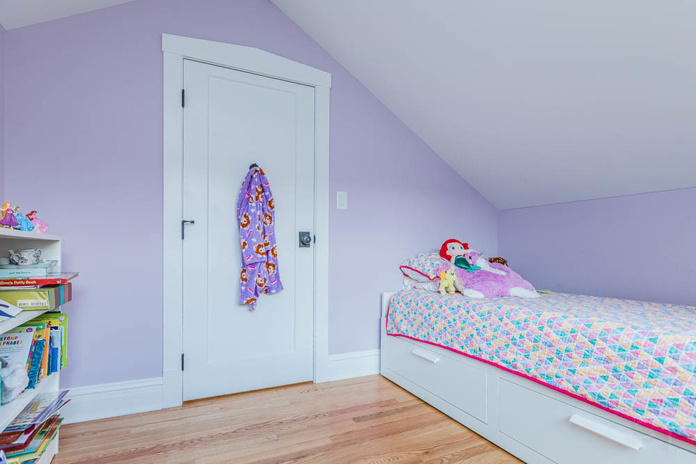 Modelo de habitación de invitados de estilo americano con paredes rosas, suelo de madera en tonos medios y suelo marrón