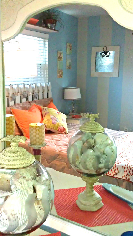 Modelo de habitación de invitados tropical pequeña sin chimenea con paredes azules y suelo de madera clara