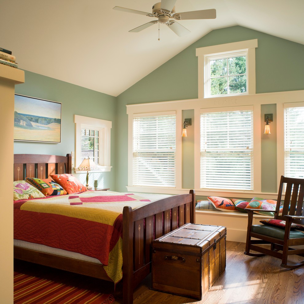 Foto på ett mellanstort amerikanskt sovrum, med gröna väggar och mellanmörkt trägolv