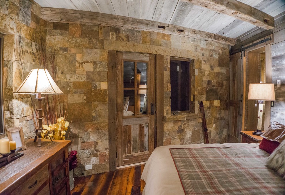 Uriges Gästezimmer mit braunem Holzboden, Eckkamin und Kaminumrandung aus Stein in Denver