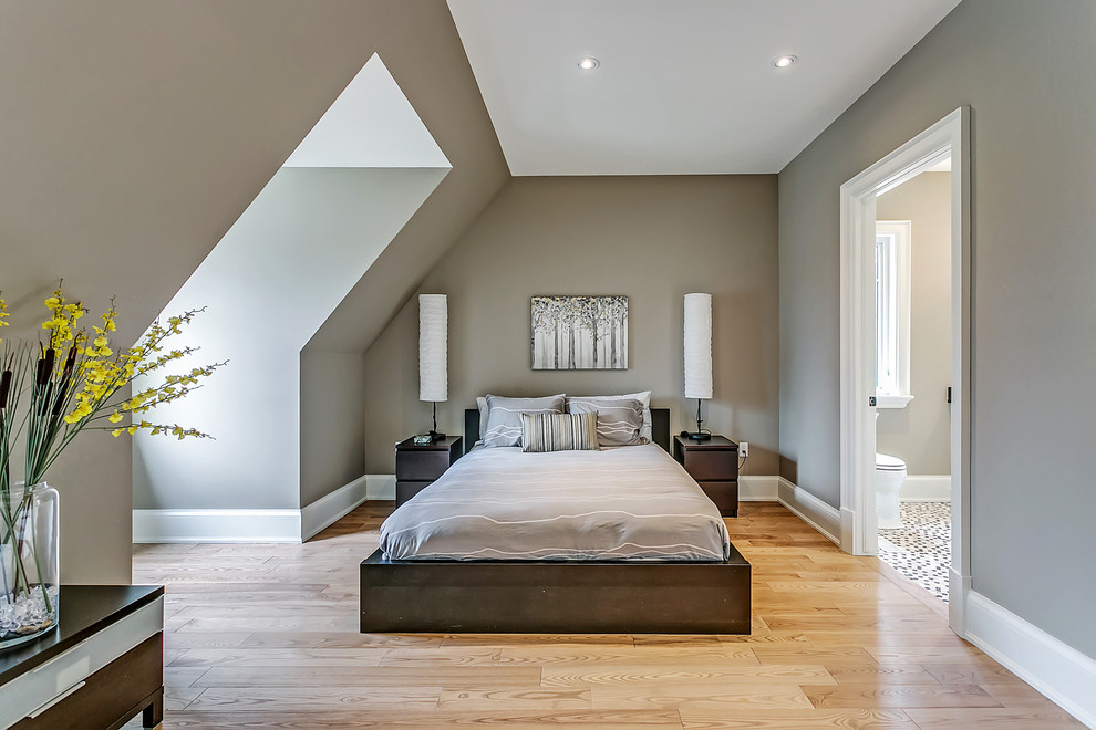 Modelo de dormitorio principal actual de tamaño medio sin chimenea con paredes grises, suelo de madera clara y techo inclinado