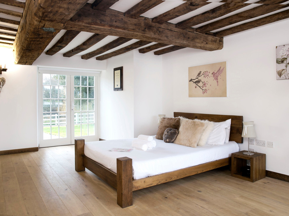 Immagine di una camera da letto country con pareti bianche, pavimento in legno massello medio e pavimento marrone