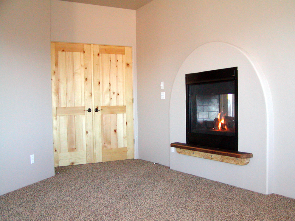 Ejemplo de dormitorio principal de tamaño medio con paredes blancas, moqueta, chimenea de doble cara y marco de chimenea de madera