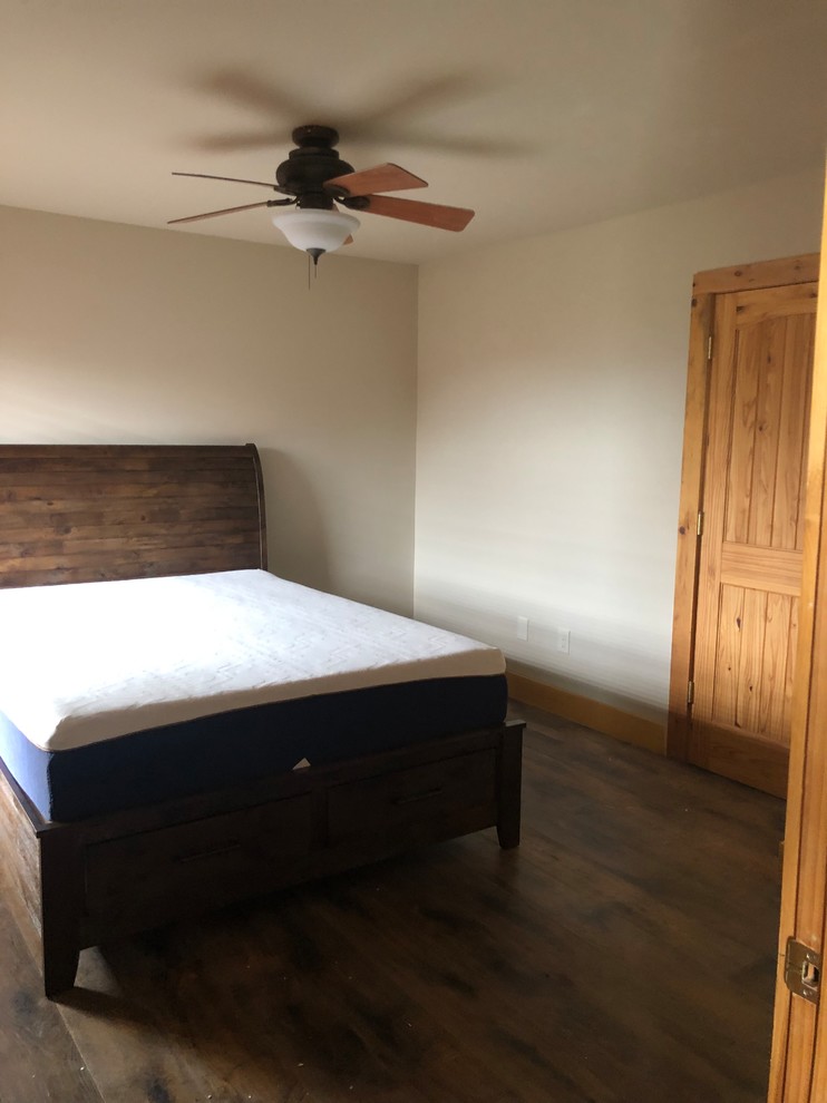 Ejemplo de dormitorio rústico grande con paredes beige, suelo de madera en tonos medios y suelo marrón