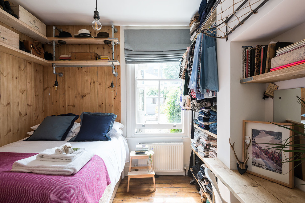 Immagine di una camera da letto rustica con pareti bianche e pavimento in legno massello medio
