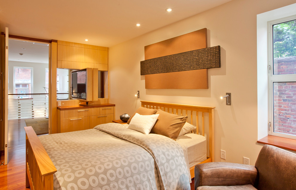 На фото: спальня в современном стиле с бежевыми стенами, паркетным полом среднего тона и телевизором