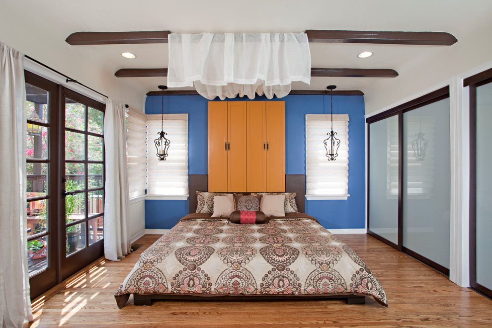 Ispirazione per una camera matrimoniale eclettica con pareti blu e pavimento in legno massello medio
