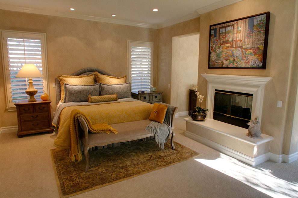 Design ideas for a large mediterranean master bedroom in Los Angeles with beige walls, carpet, a standard fireplace, a wooden fireplace surround and white floors.
