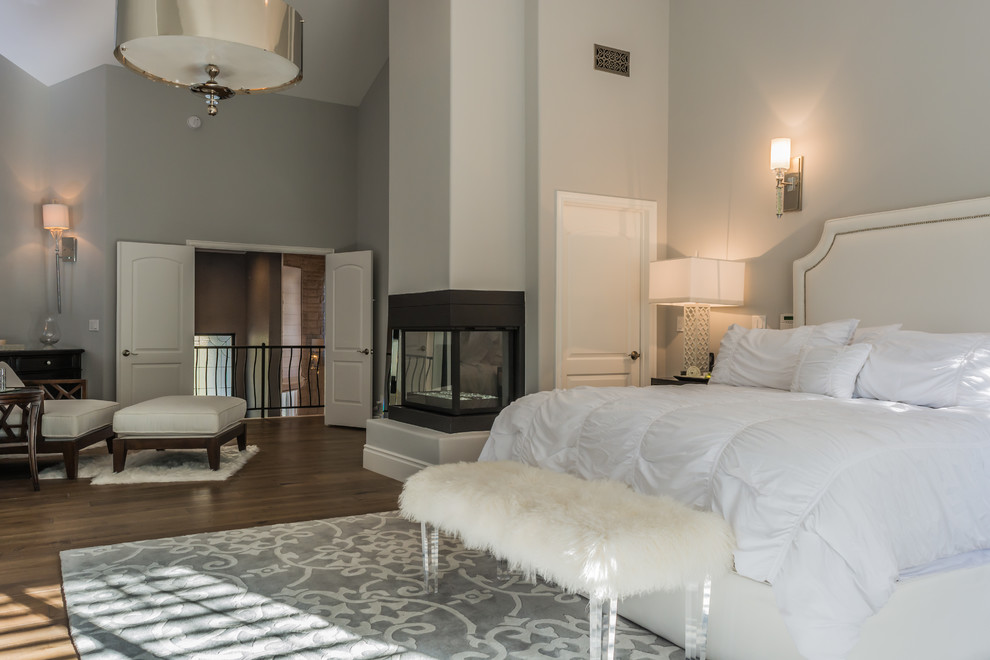 ロサンゼルスにある広いコンテンポラリースタイルのおしゃれな主寝室 (グレーの壁、濃色無垢フローリング、コーナー設置型暖炉、漆喰の暖炉まわり、茶色い床、グレーとブラウン)