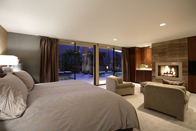 Großes Modernes Hauptschlafzimmer mit grauer Wandfarbe, Teppichboden, Kamin und Kaminumrandung aus Stein in Los Angeles