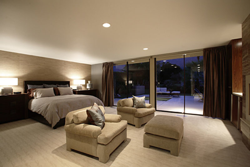 This is an example of a large contemporary master bedroom in Los Angeles with grey walls, carpet, a standard fireplace and a stone fireplace surround.