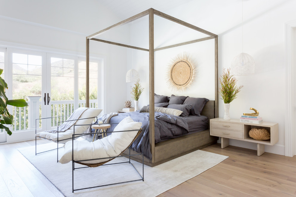 Ejemplo de dormitorio principal costero de tamaño medio sin chimenea con paredes blancas, suelo de madera clara y suelo beige