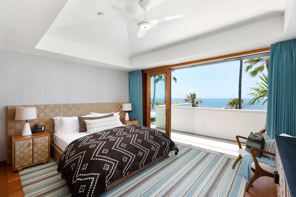 На фото: большая спальня в морском стиле с серыми стенами, паркетным полом среднего тона, коричневым полом и синими шторами без камина