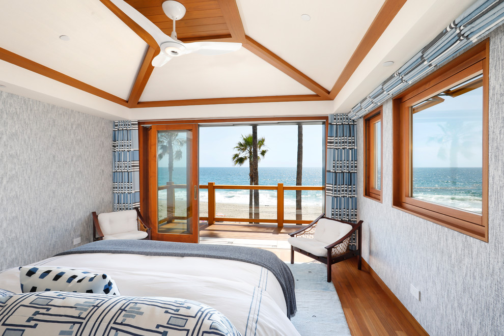 Ejemplo de dormitorio costero de tamaño medio sin chimenea con paredes grises, suelo de madera en tonos medios y suelo marrón