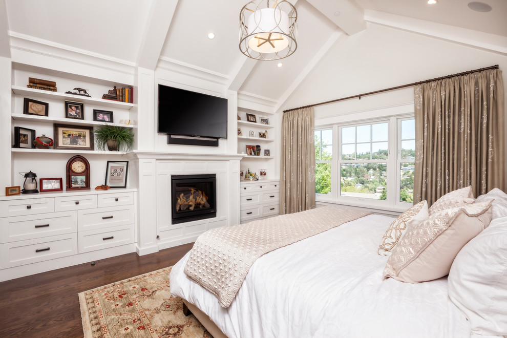 Стильный дизайн: большая хозяйская спальня в стиле кантри с белыми стенами, темным паркетным полом, стандартным камином и фасадом камина из дерева - последний тренд