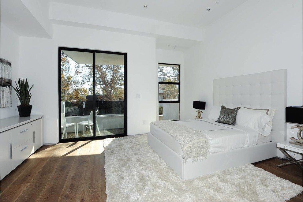 This is an example of a large modern master bedroom in Los Angeles with white walls and medium hardwood flooring.
