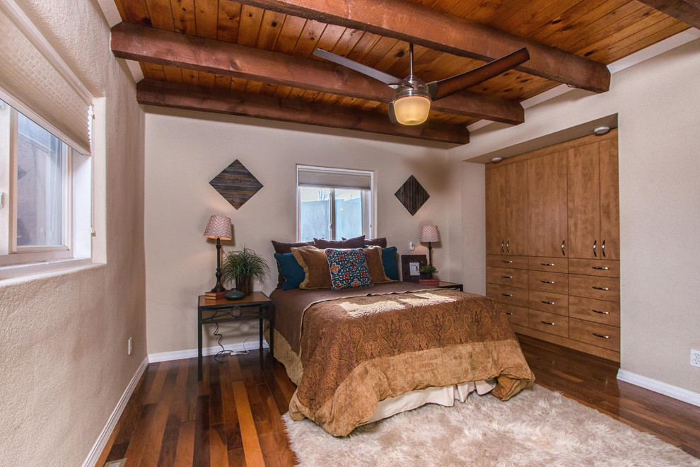 Réalisation d'une chambre parentale sud-ouest américain de taille moyenne avec un mur beige et un sol en bois brun.