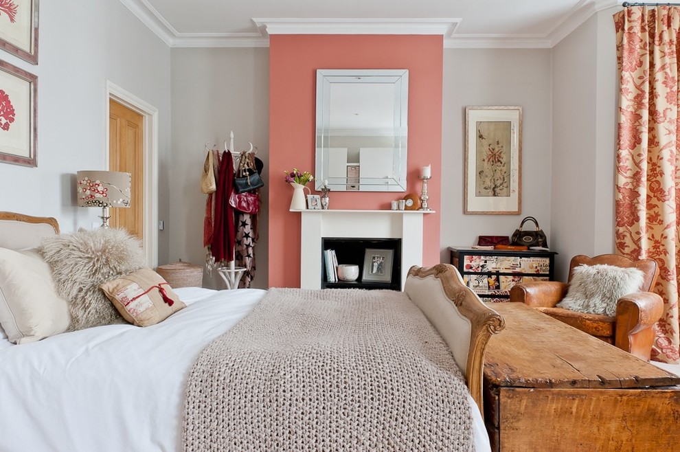 Medium sized vintage master and grey and pink bedroom in London with pink walls, carpet, a standard fireplace, a wooden fireplace surround and beige floors.