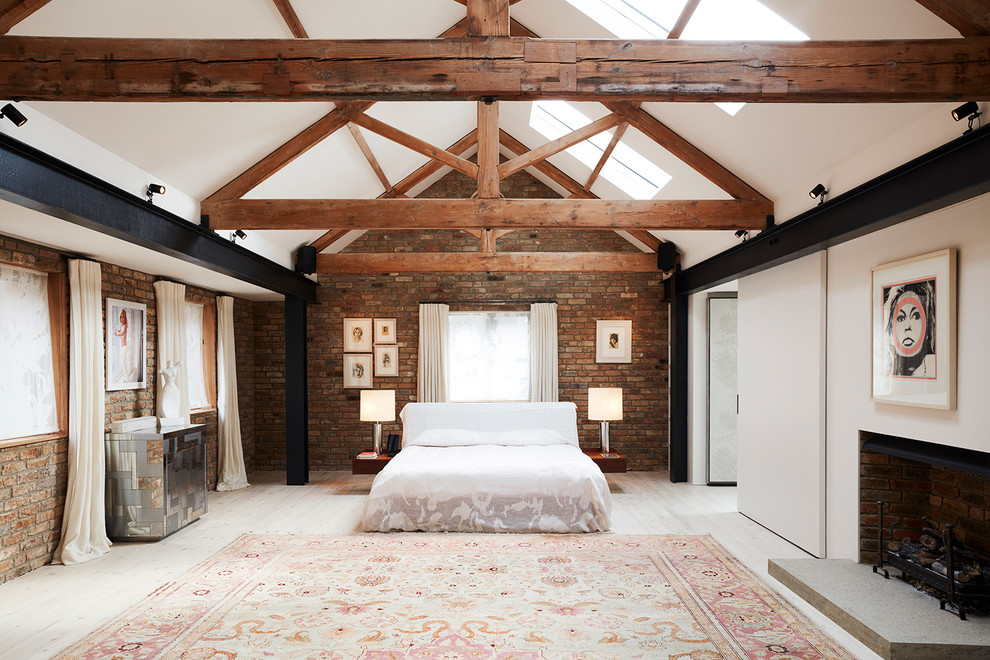 Large industrial master bedroom in London with red walls, light hardwood flooring, a standard fireplace and white floors.